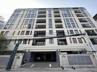 Front view of a multi-story residential building with balconies and parking area