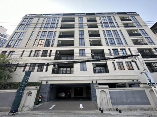 Front view of a multi-story residential building with balconies and parking area