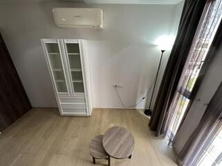 Living room view with air conditioner, small tables, and a tall white cabinet