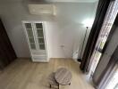 Living room view with air conditioner, small tables, and a tall white cabinet