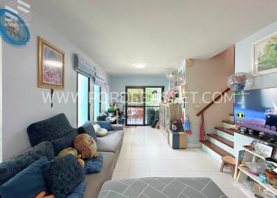 Bright living room with comfortable seating, TV, and staircase