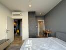 Modern bedroom with grey accent wall, light wood flooring, and minimalist decor