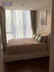 Bedroom with a large bed, floor-to-ceiling window with curtains, and framed artwork on the wall