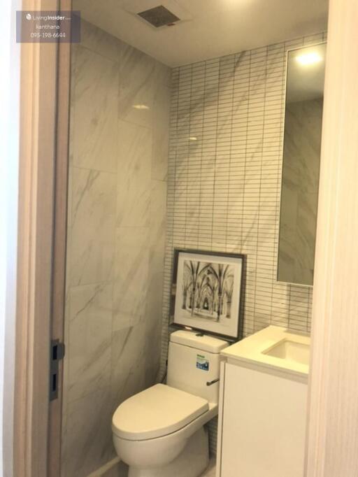 Modern bathroom with tiled walls and framed artwork