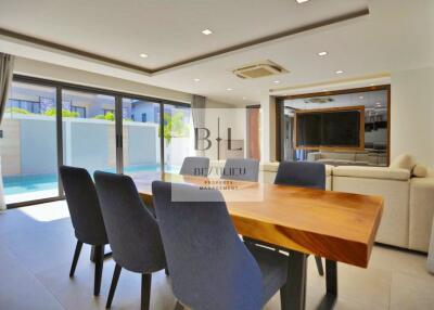 Modern and spacious living area with dining table and pool view