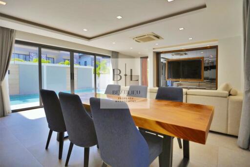 Modern and spacious living area with dining table and pool view