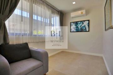 Living room with a sofa, air conditioner, wall art, and large windows with curtains