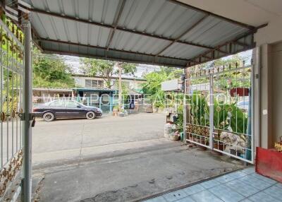 Covered garage with open gate leading to street