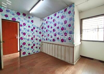 A vacant bedroom with colorful polka dot wallpaper and a window