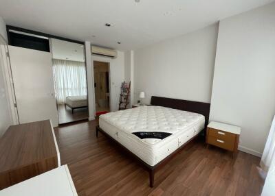 Modern bedroom with hardwood floor, bed, and mirrored wardrobe