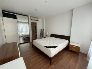 Modern bedroom with hardwood floor, bed, and mirrored wardrobe