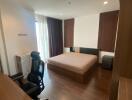 Spacious and modern bedroom with a large bed, office chair, and ample natural light from large window