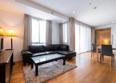 Modern living room with a sofa, coffee table, TV, and large windows with curtains