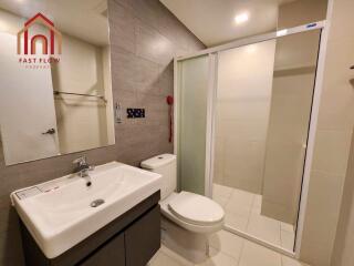 Modern bathroom with sink, toilet, and shower area.