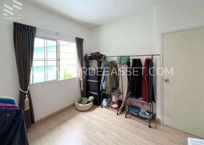 Bedroom with window, clothing racks, and hardwood floor