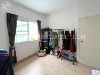 Bedroom with window, clothing racks, and hardwood floor