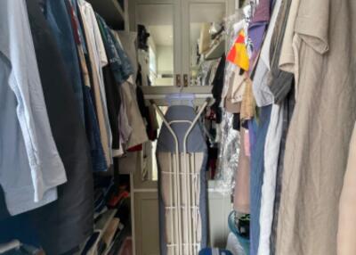 Walk-in closet filled with clothes and ironing board