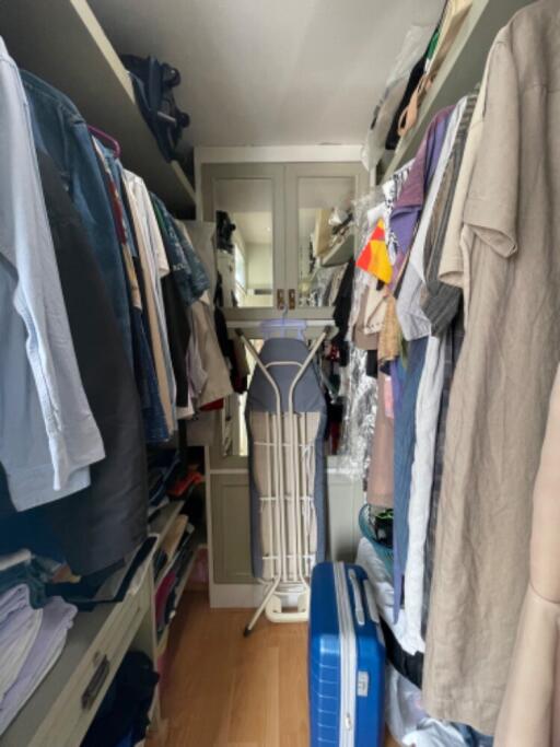 Walk-in closet filled with clothes and ironing board