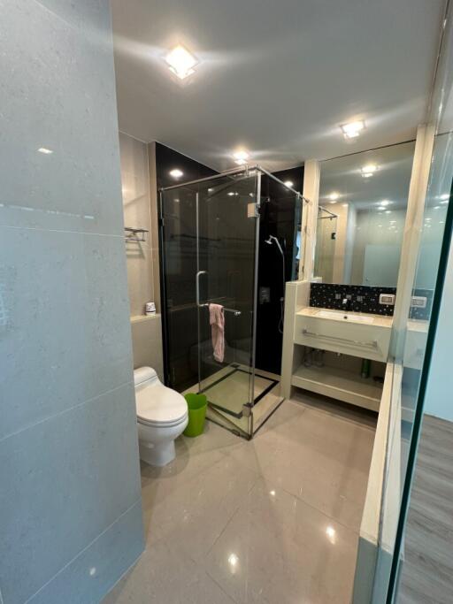 Modern bathroom with glass shower enclosure, toilet, and vanity