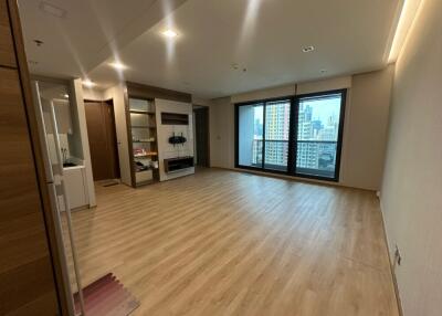 Spacious living room with wooden flooring, large window, storage units, and a small kitchenette