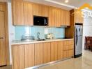 Modern kitchen with wooden cabinets, modern appliances, including a refrigerator and microwave, and a dining area.