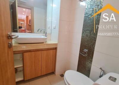 Modern bathroom with sink, mirror, toilet, and wooden cabinets