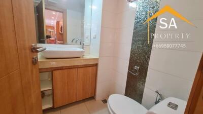 Modern bathroom with sink, mirror, toilet, and wooden cabinets