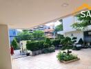 Covered outdoor area leading to a building entrance with greenery