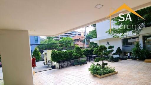 Covered outdoor area leading to a building entrance with greenery