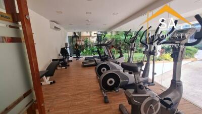 Well-equipped gym with modern exercise machines and large windows overlooking a garden