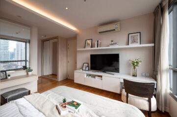 Modern bedroom with TV, desk, and large window