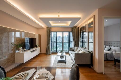 Modern living room with wooden flooring, large window, and connected bedroom