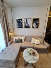 Modern living room with beige sectional sofa, wall art, and marble coffee table