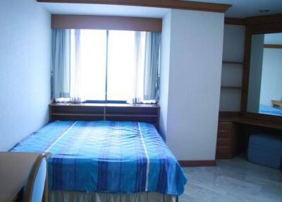 Bedroom with a large window, blue bedspread, and wooden furniture