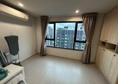 Well-lit bedroom with wooden flooring, large window with city view, and built-in wardrobe