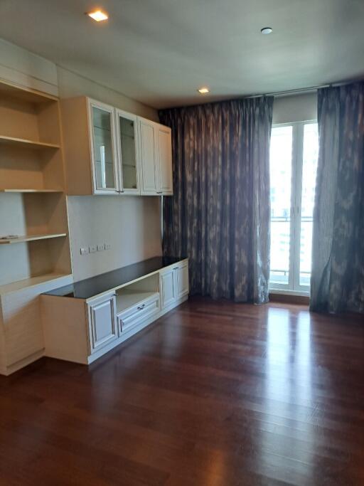 empty living room with built-in cabinets and large windows