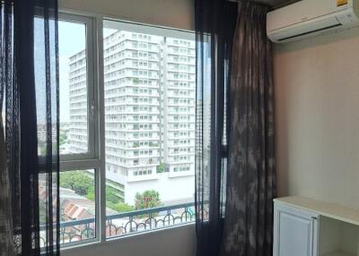 Bedroom with large window and view of buildings outside