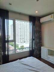 Bedroom with large window and view of buildings outside