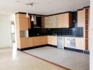 Modern kitchen with light wood cabinetry and black backsplash