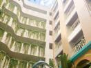 Courtyard of a multi-storey residential building with balconies covered in plants