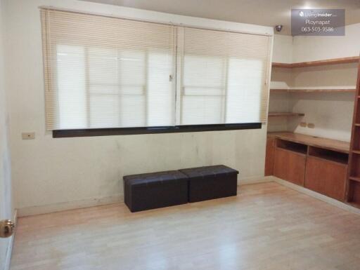 A minimalistic living area with wooden floor and shelves.