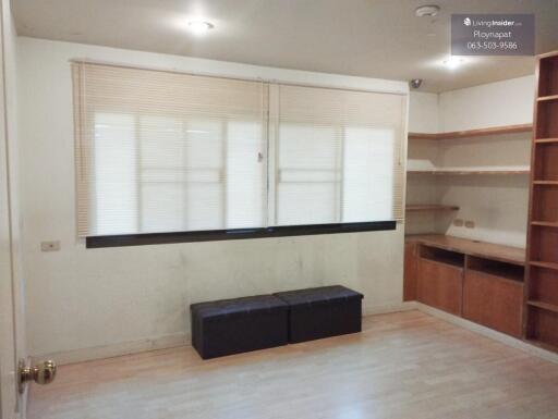 Spacious living room with window blinds and built-in wooden shelves