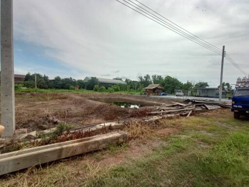 vacant lot with construction materials and a nearby structure