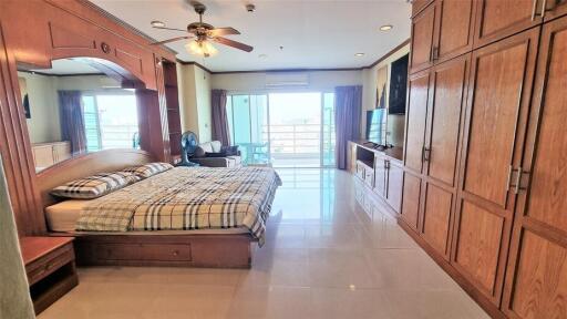 Spacious bedroom with large wooden wardrobe and balcony