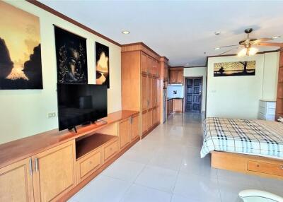 Spacious master bedroom with wooden cabinetry and integrated entertainment system