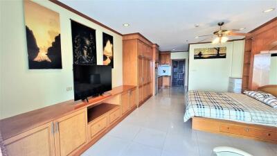 Spacious master bedroom with wooden cabinetry and integrated entertainment system