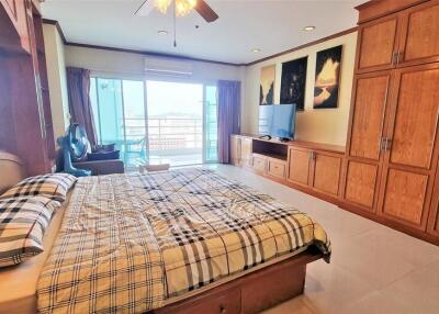 Spacious and well-lit bedroom with large bed, wooden wardrobe and balcony access