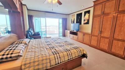 Spacious and well-lit bedroom with large bed, wooden wardrobe and balcony access