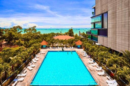 Outdoor swimming pool with lounge chairs and view of the beach