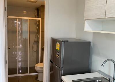 Small kitchen with fridge and sink next to a bathroom